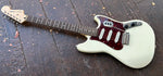 Side view , top rosewood fretboard, squier headstock with metal tuners, white body with metal tremolo, white pick ups, with tortoise pick guard cover 