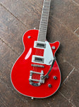 Close up, top view: Red body Gretsch with metal Bigsby tremolo, with two humbucker black pick ups, three knobs silver
