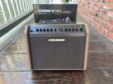 Fishman Loudbox Mini Charge brown amplifier on a wooden surface with a brick wall in the background