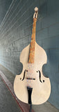 Tan Double bass leaning against a gray brick wall