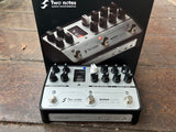 Two guitar effect pedals with multiple knob controls, silver and black on a wooden surface with 'Two Notes Audio Engineering' branding.