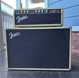 A vintage Fender bassman guitar amp with speaker  cabinet, photographed outdoors on a porch.