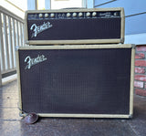 A Fender Tremolux  Head Amp blond head and matching speaker cabinet stacked outdoors on a porch. The amps feature beige jumbo tweed covers, black front grilles, and silver Fender logos.