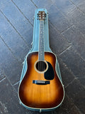 A Martin D-35 acoustic guitar with a sunburst finish, resting inside its light blue-gray hard case on a dark wooden plank floor.