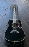 1977 Gibson Dove Acoustic guitar in black finish with dove inlay pick guard resting on case, displayed on wooden floor