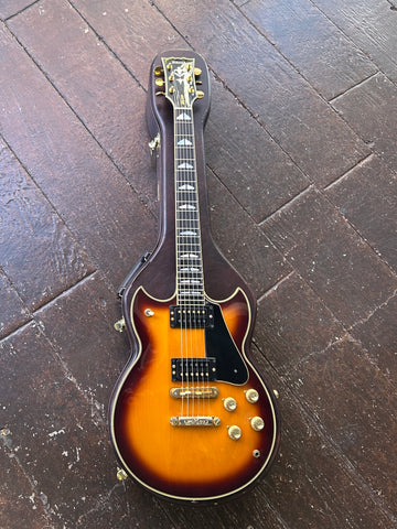 Electric guitar with a sunburst finish on a dark wooden floor