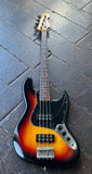Fender sunburst electric bass guitar with black pick guard maple headstock, rosewood fretboard on wooden floor