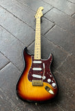 2014 Fender Stratocaster electric guitar with a sunburst finish, maple fretboard and headstock resting on a dark wooden plank floor.