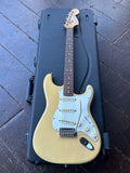 Fender Stratocaster electric guitar vintage blond finish resting on top of its black hard case, placed on a dark wooden deck.