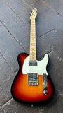 A classic Fender Telecaster with Humbcuker electric guitar in a sunburst finish, maple neck and headstock resting on a dark wooden plank floor.