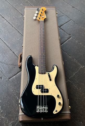 Fender Precision bass Black bass guitar in a brown case on a dark textured floor