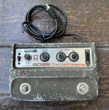 Vintage grey BOSS Chorus Ensemble guitar effects pedal on a wooden surface with a coiled cable.