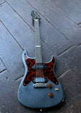 Blue electric guitar with a leopard print pickguard on a dark stone surface