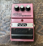Pink DOD bass compressor pedal with three knob controls on a textured surface