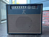 A black DR. Z Maz 18 watt guitar amplifier with a textured front grille and control knobs, photographed outdoors on a porch with a brick wall and railing in the background.