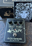 Electro-Harmonix Gains Vibe Modulator guitar pedal in black with white lettering and silver controls, shown with its packaging box and printed insert on a dark textured surface.