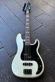 A Fender White pearl electric precision  bass guitar with a black pickguard and dark fretboard, photographed from above on a dark wooden plank floor.