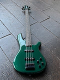 Green Fernandez electric bass guitar with rosewood fingerboard and black hardware on a gray tiled floor