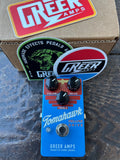 Greer Amps Tomahawk Blue Deluxe Drive guitar effects pedal in blue with black knobs, shown in front of its cardboard box and branded stickers on a stone surface.
