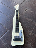 Gretsch electromatic lapsteel guitar in white, chrome hardware, black plastic fretboard and white headstock, displayed on wooden floor