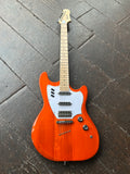 Guild Orange electric guitar with white pick guard three pick ups a dark tiled floors, maple neck