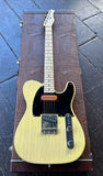 A High Spirit t syle electric guitar with a natural wood finish and black pickguard, resting on top of its brown textured hard case on a dark wooden deck.