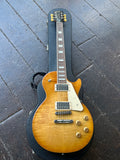 2024 Gibson Les Paul Studio Figured Honey Burst electric guitar with chrome hardware and rosewood fretboard, black headstock on case resting on wooden floor