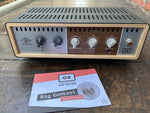 Audio amplifier with control knobs on a wooden surface, accompanied by an 'OX' branded card.