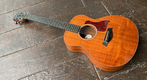 Top view Mahogany Taylor GS Mini with tortoise pick guard, ebony fretboard, pearl dots , black headtock with Taylor script