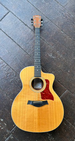 Top view Taylor acoustic spruce top, red tortoise shell pick guard, ebony bridge, ebony fret board with pearl fret dot markers, rosewood headstock 