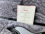 Fender certificate of authenticity on a textured gray surface with a guitar neck.