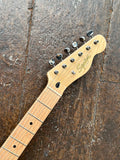 close up Squier headstock, six in line chrome tuners, with Squier gold logo
