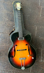 Top view Gretsch sunburst guitar resting on grey case. Gretsch guitar with single pick up, two clear control knobs, rosewood fretboard , Gretwsch black hear stock with off white button tuners 
