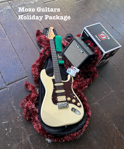 An electric guitar with a sunburst finish laying on a gig bag, surrounded by holiday decorations and a portable modeling amp.