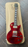 Top view Gibson Les Paul wine red with chrome hardware, two pick ups, rosewood neck, trapezoid inlays, resting on gold rectangle case 
