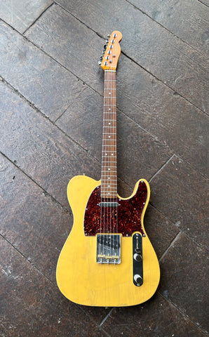 Top view: yellow telecaster with tortoise pick guard, metal control plate, two pick ups, rosewood fretboard, gloss headstock with Fender script