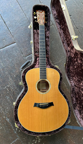 top view Taylor cedar top guitar in case, ebony bridge, soundhole, with rosewood fretboard. Taylor rosewood headstock