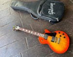 Full shot of 2022 Gibson Les Paul Studio Tangerine Burst next to included gig bag