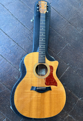 Top view: Taylor acoustic spruce top, with cutaway, tortoise pick guard, ebony bridge, rosewood fretboard with dot inlays, roswood headstock, with Taylor script in white 