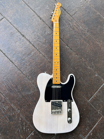 front view Aged white telecaster with black pick guard, with  finished maple fret board and Squier in gold script on maple headstock