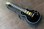 top side view Black les paul with three gold humbucker picks, gold hardware, white binding, abalone inlays, black headstock with gold tuners