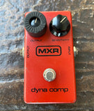 Red MXR dyna comp guitar effects pedal on a textured surface
