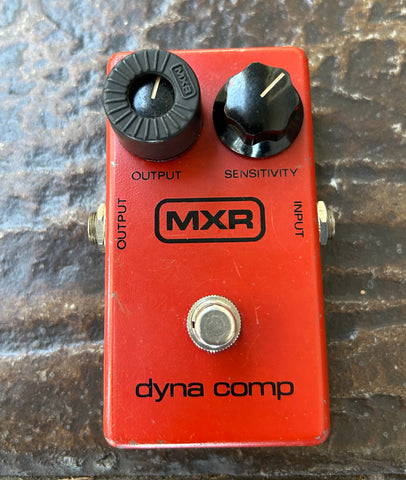 Red MXR dyna comp guitar effects pedal on a textured surface
