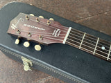 Close up brown headstock with Harmony and rocket script with white tuning pegs