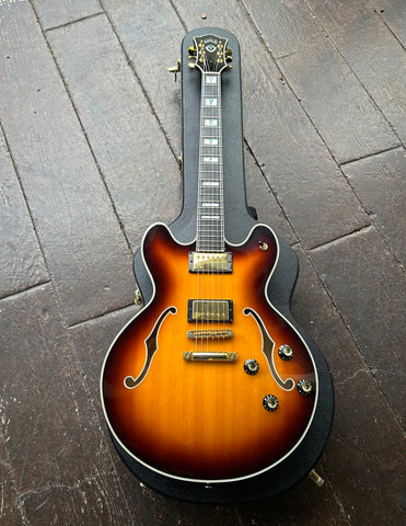 Top view Tobacco sunburst Guild archtop, with gold pick ups and hardware, ebony neck with pearl block inlays, black guild headstock with gold machine tuners