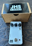 White JHS 3 Series delay pedal on a dark surface with packaging in the background