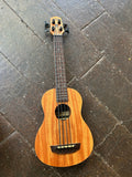 Kala U-bass wooden ukulele on a dark tiled floor