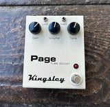Kingsley Page tube boost guitar pedal in off white, three control knobs, single metal footswitch button on wooden floor
