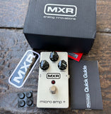 An MXR micro amp + guitar pedal shown with its black branded box, quick guide booklet, sticker, and small black accessories on a rustic wooden surface.