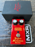An MXR Vinygie Malmsteen Overdrive guitar pedal in red with gold lettering and black knobs, shown with its black branded box and an MXR sticker on a dark wooden surface.